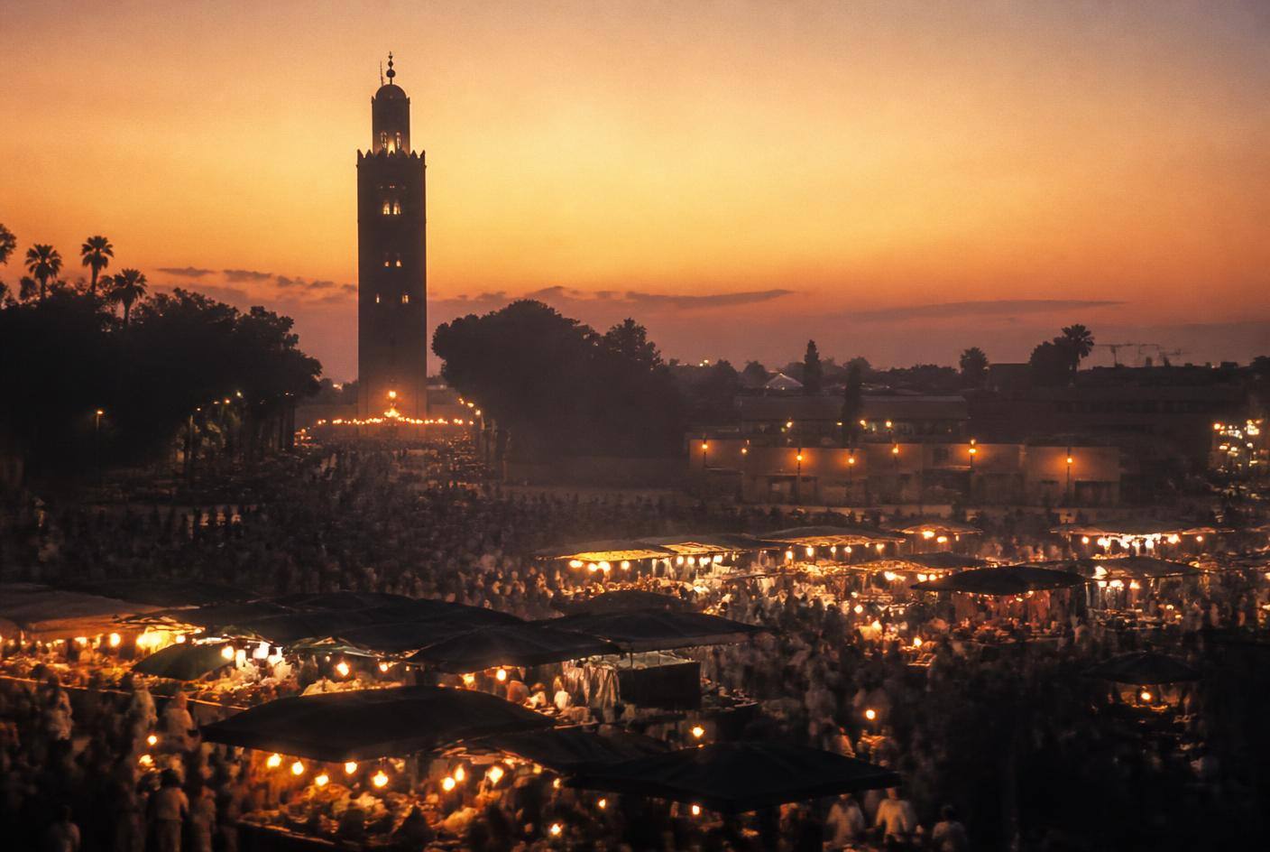 Marrakech medina at dusk with the Koutoubia minaret and lantern-lit market street